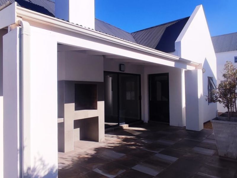 A well-maintained covered patio featuring tiled flooring and a built-in braai, providing a seamless transition to the interior living space.