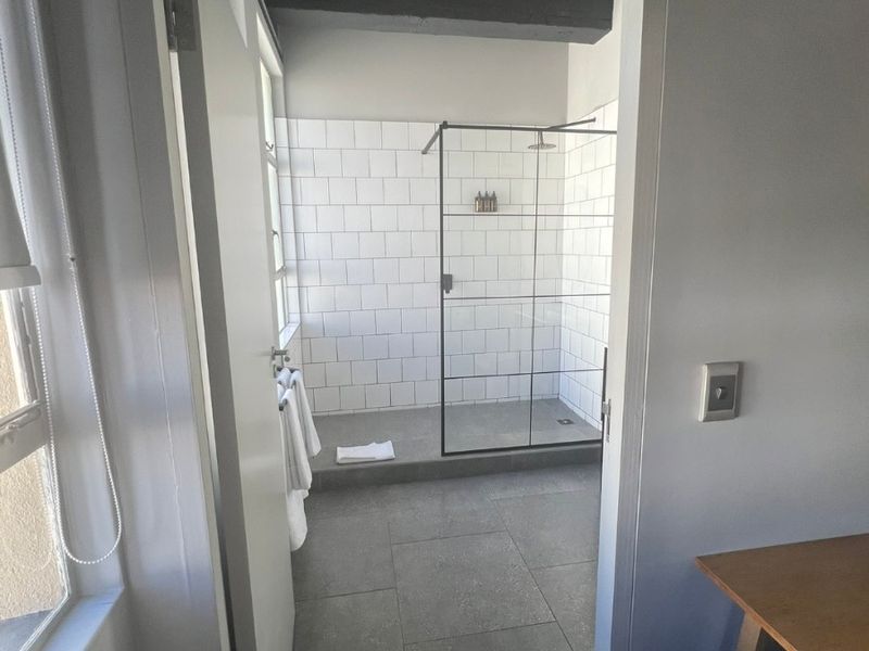 A modern bathroom featuring a walk-in shower with a black-framed glass screen and white subway-style wall tiles.