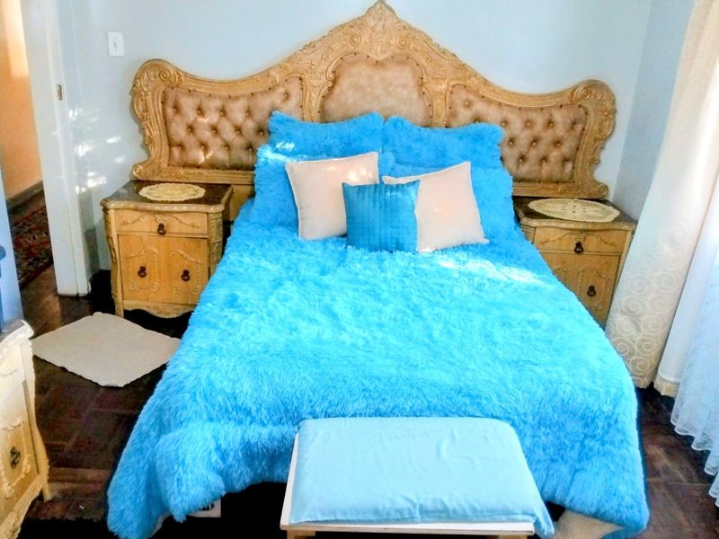 A bedroom featuring dark hardwood flooring and a prominent decorative headboard.
