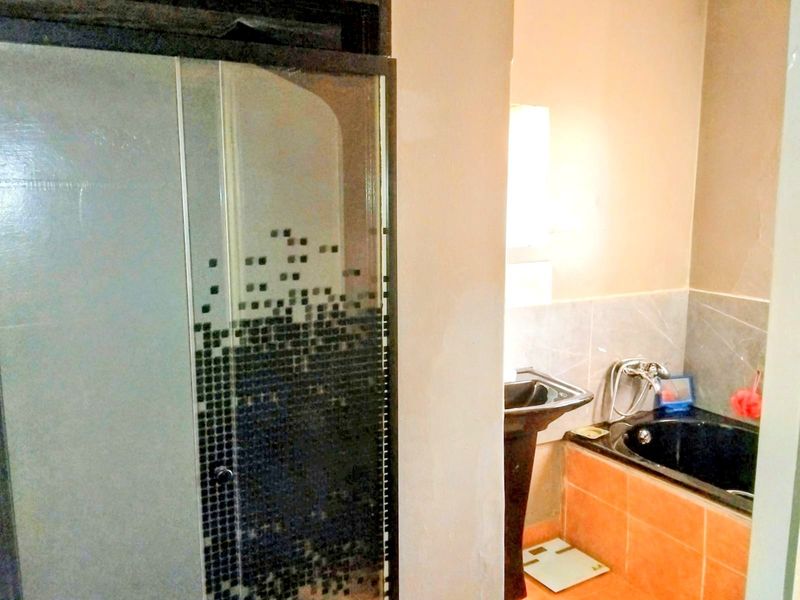 A bathroom featuring a shower enclosure, pedestal basin, and built-in bathtub with dated tile finishes.