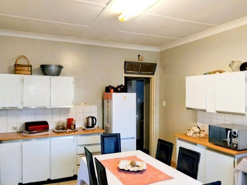 A functional kitchen featuring white built-in cabinetry, laminate countertops, and a tiled backsplash, offering a practical layout for daily meal preparation.