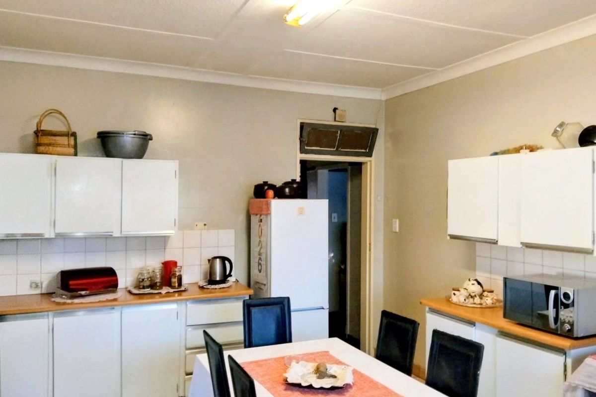 A functional kitchen featuring white built-in cabinetry, laminate countertops, and a tiled backsplash, offering a practical layout for daily meal preparation.