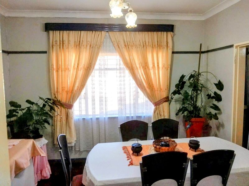 A dining room featuring a window with curtains, coving, and a picture rail, providing a functional space for meals.