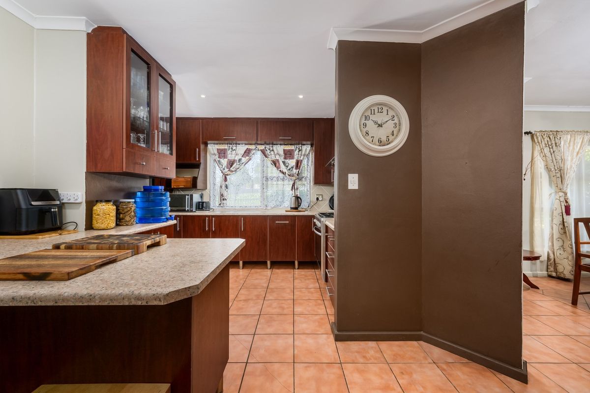 A functional kitchen featuring dark wood cabinetry, laminate countertops, and ceramic tiled flooring, offering a practical layout with integrated cooking appliances.