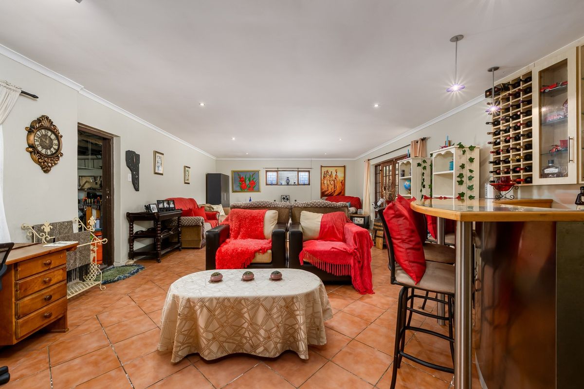 Spacious living area featuring terracotta floor tiles, recessed lighting, and a built-in bar with integrated wine storage.