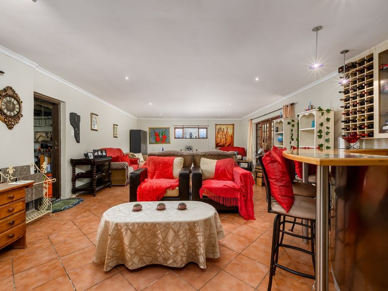 Spacious living area featuring terracotta floor tiles, recessed lighting, and a built-in bar with integrated wine storage.