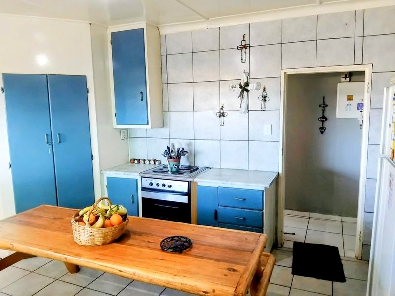 A functional kitchen featuring blue built-in cabinetry, a tiled splashback, and a built-in oven with hob, offering potential for modern updates.