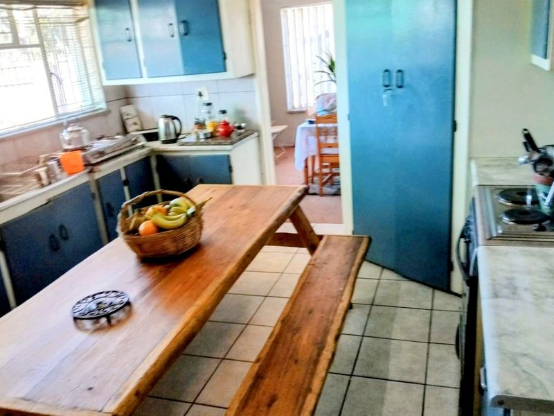 A dated kitchen featuring tiled flooring, built-in cabinetry, and a built-in hob, offering potential for a modern renovation.