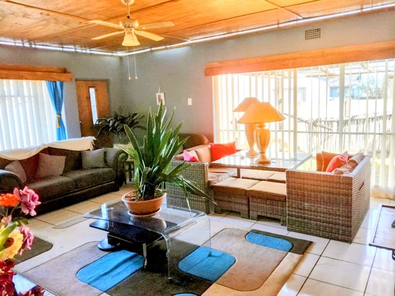 Spacious living room featuring tiled flooring, timber ceiling panels, a ceiling fan, and large sliding glass doors providing natural light.