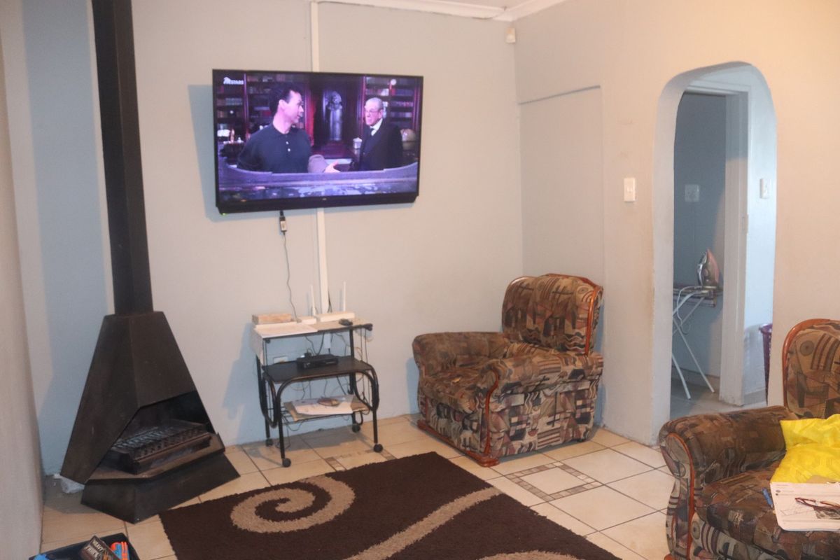 Living room featuring a freestanding fireplace, ceramic tiled flooring, and an arched doorway leading to an adjacent space.