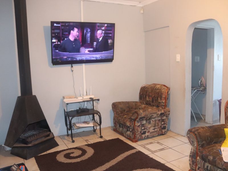 Living room featuring a freestanding fireplace, ceramic tiled flooring, and an arched doorway leading to an adjacent space.