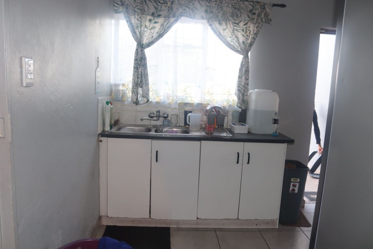 A compact kitchen area featuring a double sink, tiled splashback, and basic built-in base cabinetry with a laminate countertop.