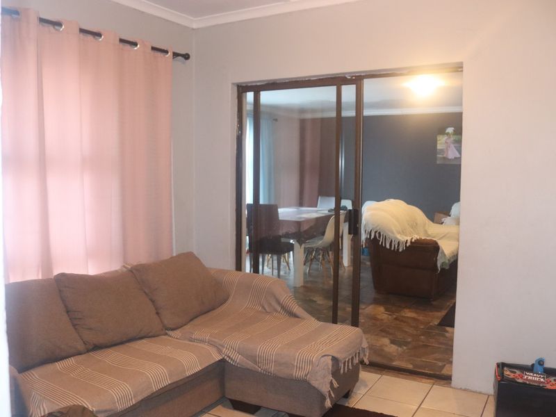 A living room area featuring tiled flooring and a sliding glass door leading to an adjacent dining space.