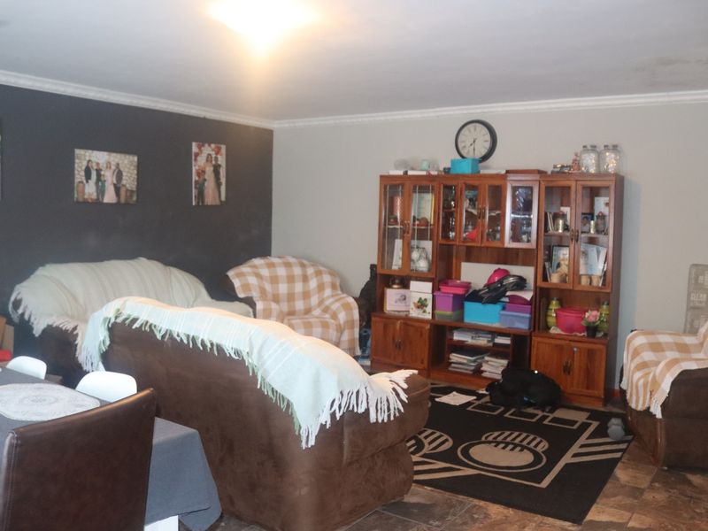 A living room area featuring tiled flooring and ceiling cornicing, currently showing signs of water damage on the ceiling.