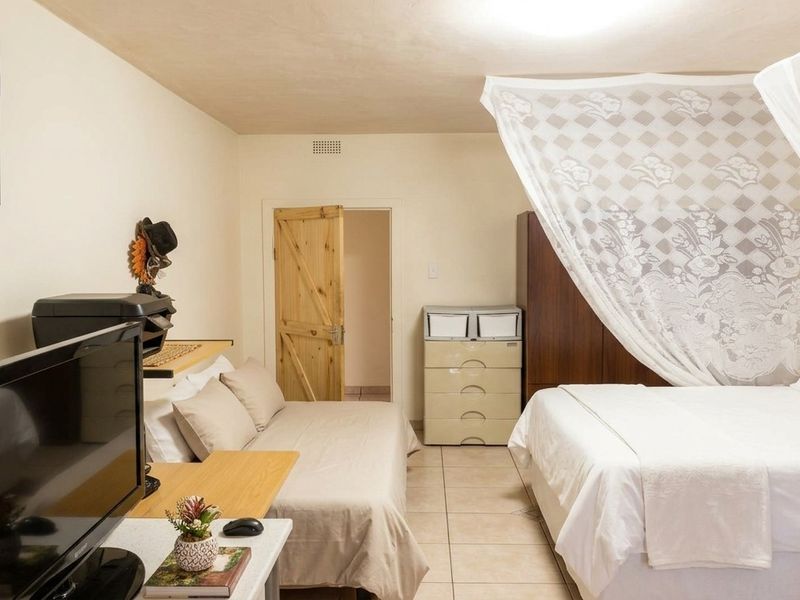 A functional bedroom featuring tiled flooring and a wooden door, providing a neutral base for potential interior updates.
