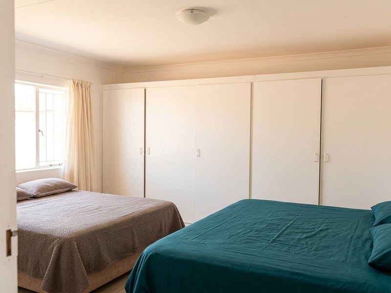 A bedroom featuring extensive white built-in cupboards and cove cornice detailing, providing ample storage space.