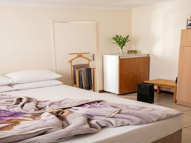 A functional bedroom featuring tiled flooring and a built-in cupboard, offering a clean and simple living space.