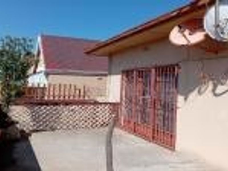 An outdoor concrete patio area featuring a security gate, lattice privacy screen, and mounted satellite dish.