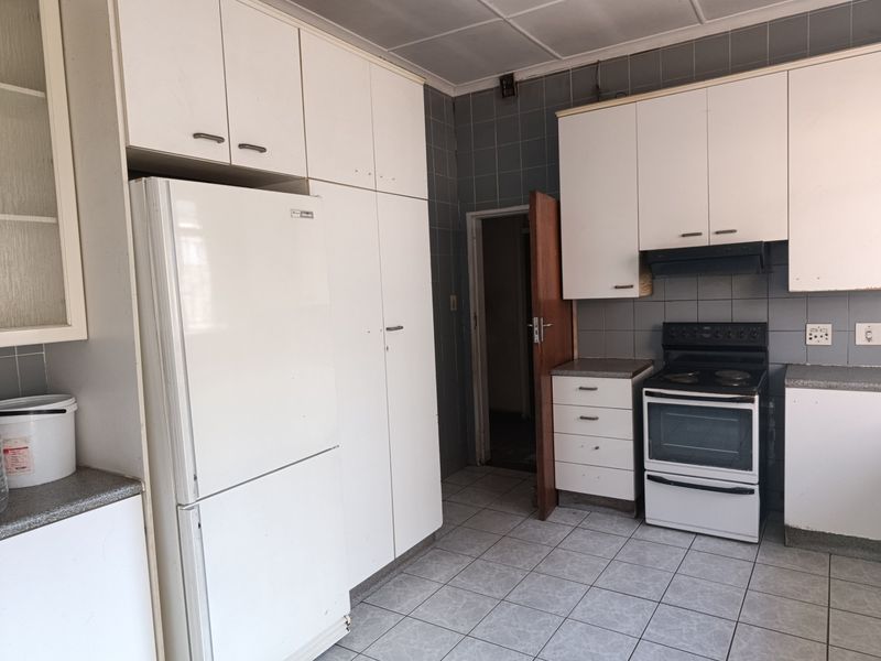 A functional kitchen featuring white built-in cabinetry, tiled flooring, and a tiled backsplash, offering a dated aesthetic ready for modernization.