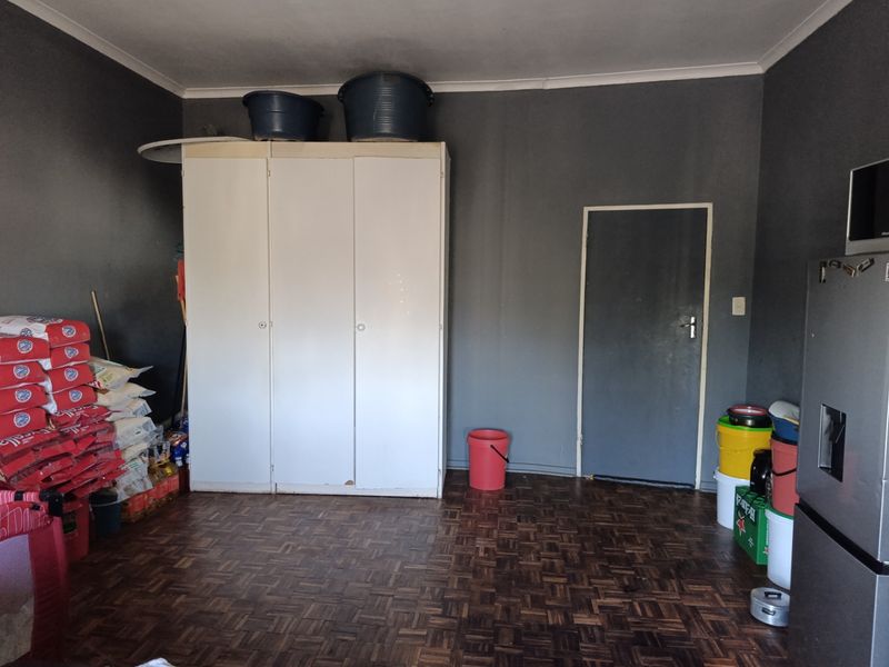 A utility space featuring dark grey walls and parquet flooring, equipped with a large built-in cupboard for storage.