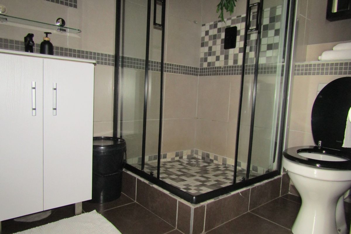 A modern bathroom featuring a glass-enclosed shower, vanity cabinet, and tiled finishes throughout.