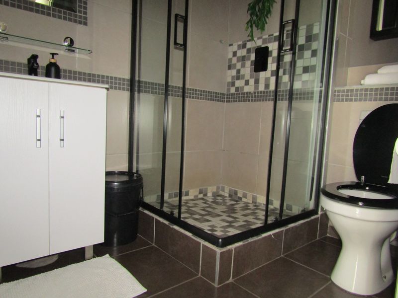 A modern bathroom featuring a glass-enclosed shower, vanity cabinet, and tiled finishes throughout.