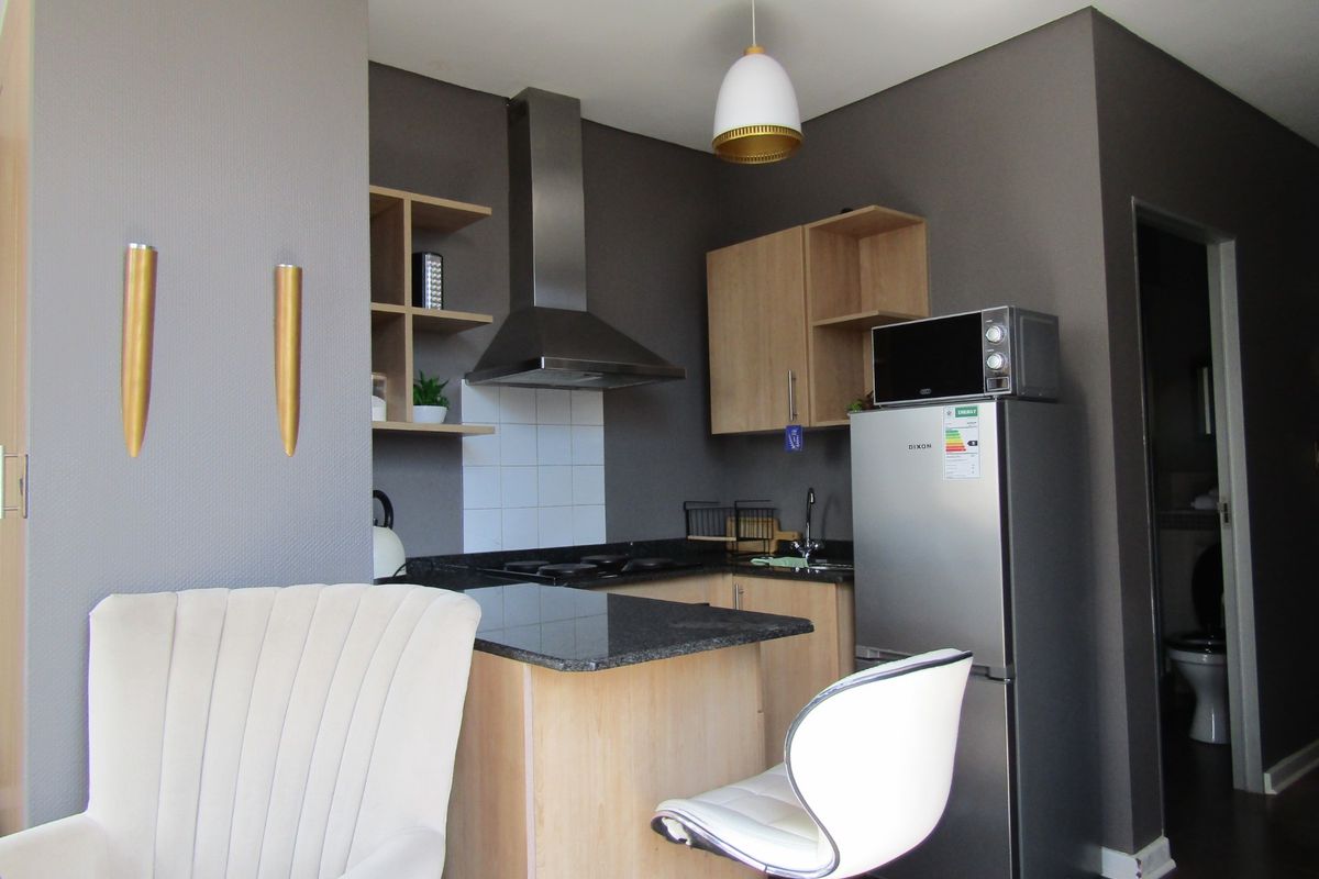 Compact kitchen featuring modern dark grey walls, light wood cabinetry, granite countertops, and a stainless steel extractor fan.