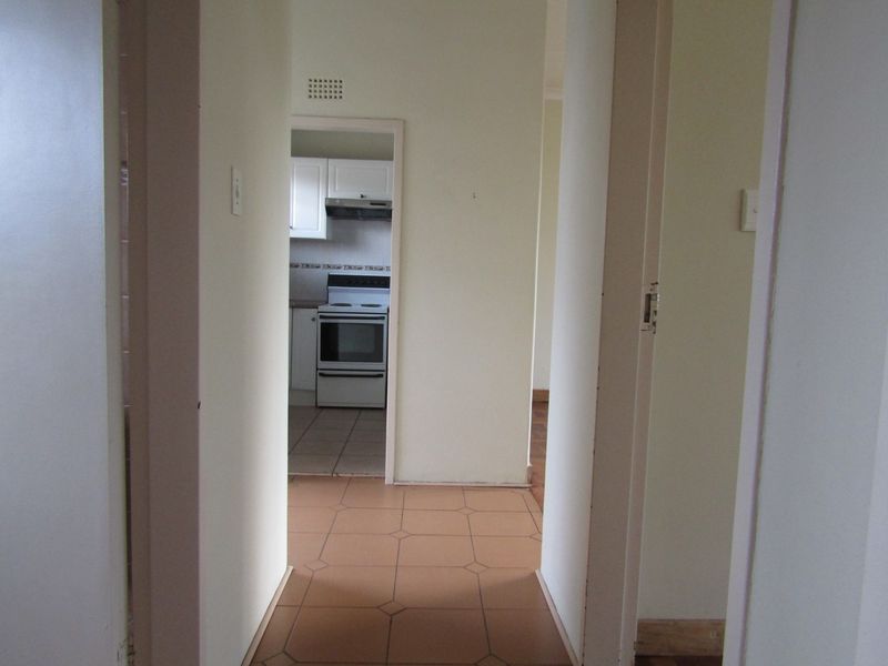 A functional hallway with tiled flooring providing access to the kitchen area, featuring neutral wall finishes and standard architectural layout.