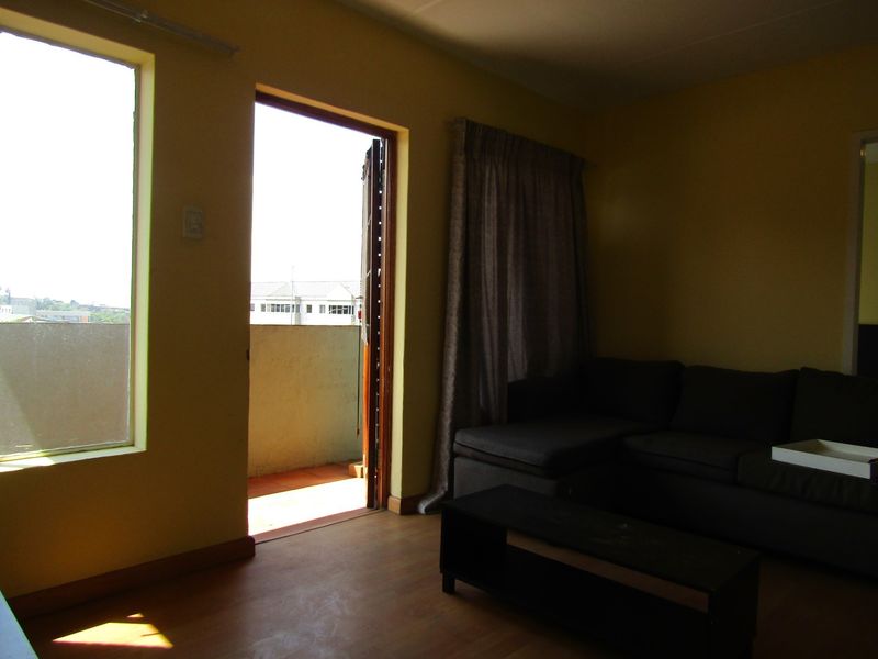Living room area featuring laminate flooring and direct access to a private balcony, providing natural light and outdoor connectivity.