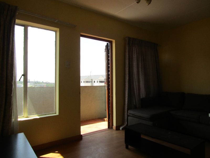 A living room area featuring laminate flooring and direct access to an outdoor balcony through a sliding door.