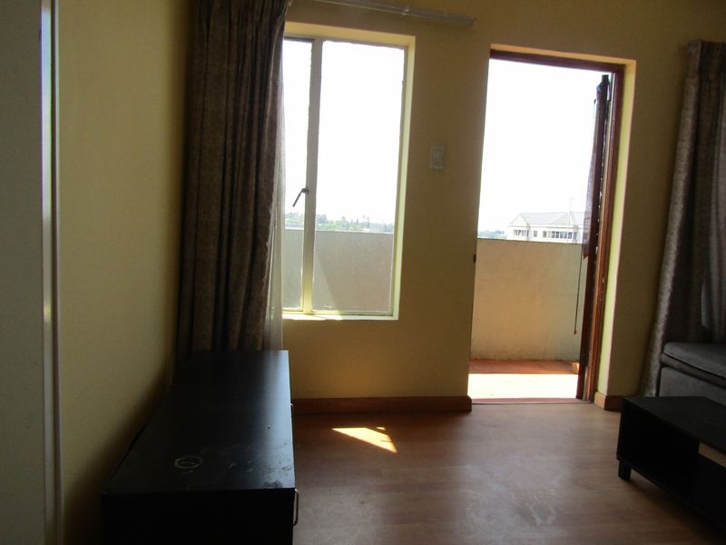 Living room area featuring laminate flooring and direct access to an outdoor balcony through a sliding door.