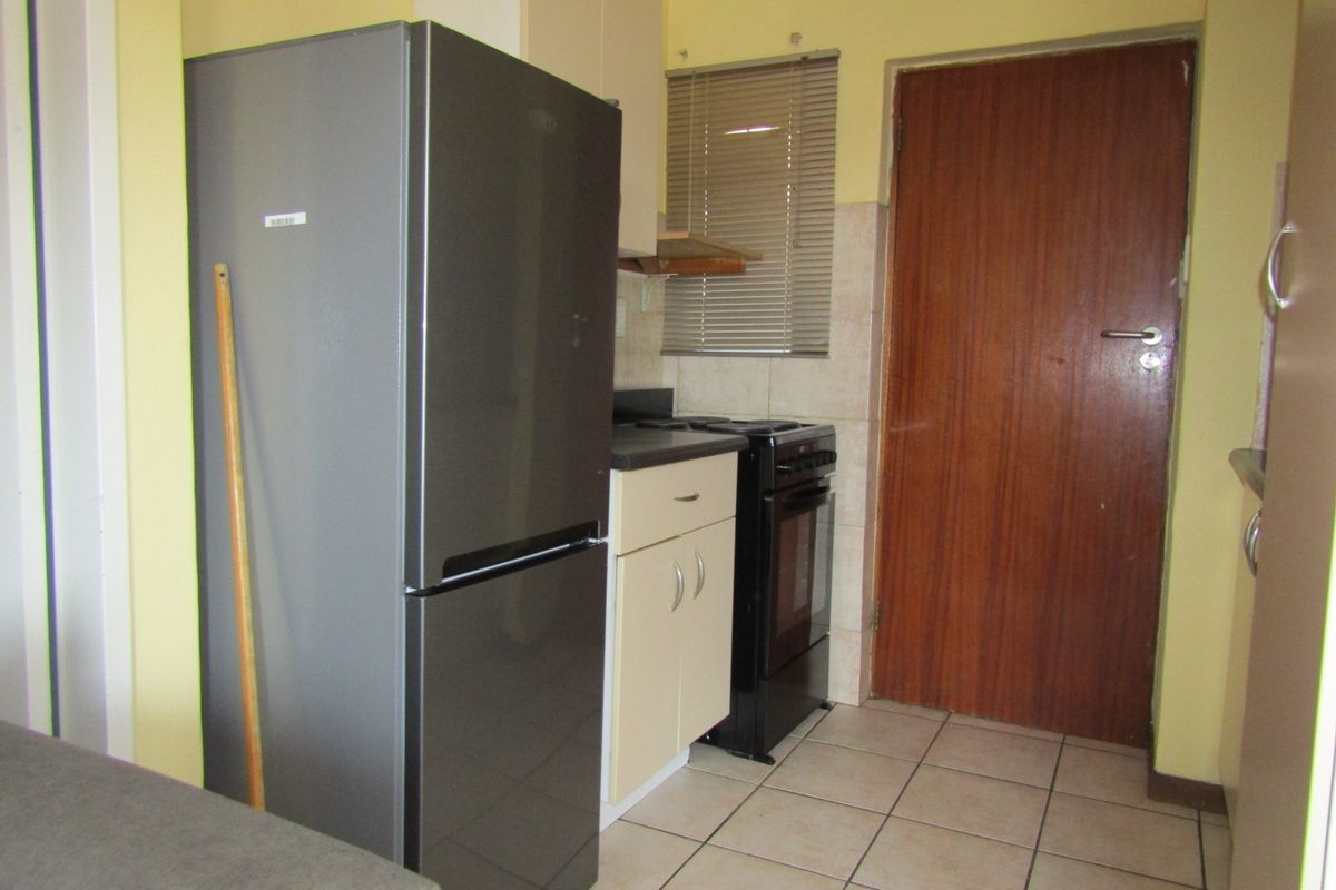 Compact kitchen featuring tiled flooring, built-in cabinetry, a tiled backsplash, and a freestanding stove, offering a functional layout for daily meal preparation.
