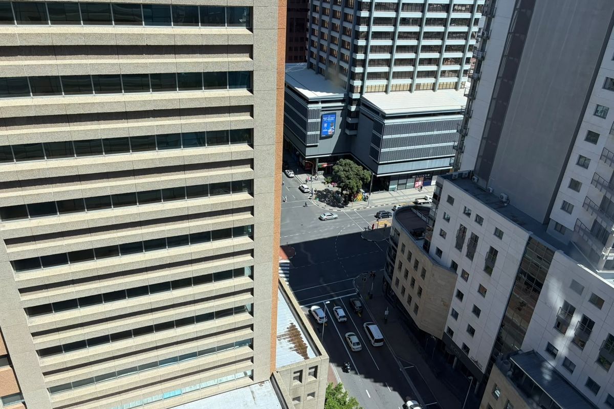 An elevated aerial view looking down onto a busy urban street intersection surrounded by high-rise commercial office buildings.