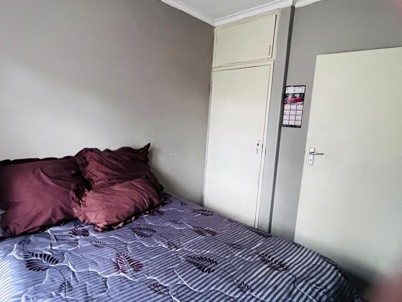 A bedroom featuring a built-in cupboard with overhead storage and a standard internal door, finished with neutral wall paint.