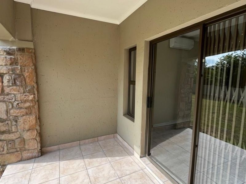 Covered patio area featuring tiled flooring, a stone-clad feature wall, and a large sliding glass door providing access to the interior.