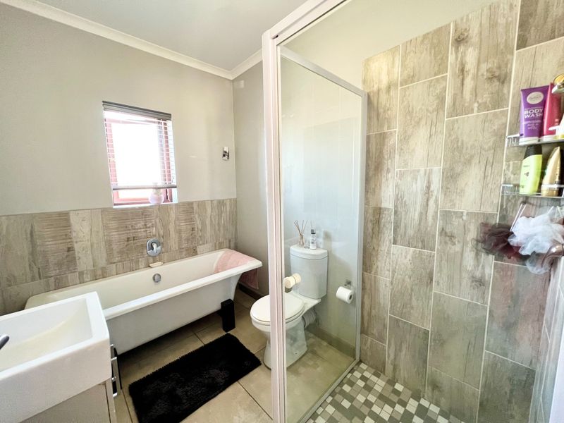 Modern bathroom featuring a freestanding bathtub, a separate walk-in shower with glass enclosure, a toilet, and a vanity basin with neutral tiled finishes.