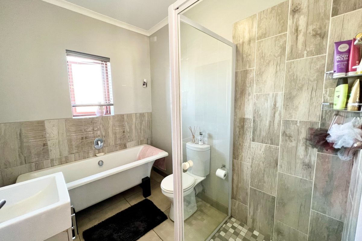 Modern bathroom featuring a freestanding bathtub, a separate walk-in shower with glass enclosure, a toilet, and a vanity basin with neutral tiled finishes.