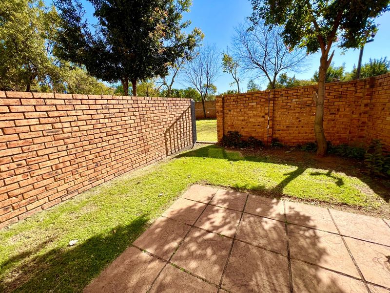A private rear garden featuring a paved patio area, established lawn, and secure brick boundary walls.