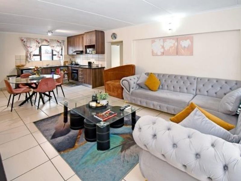 Spacious open-plan living area featuring a modern kitchen with built-in cabinetry, integrated oven, and tiled flooring throughout, creating a functional and cohesive living space.
