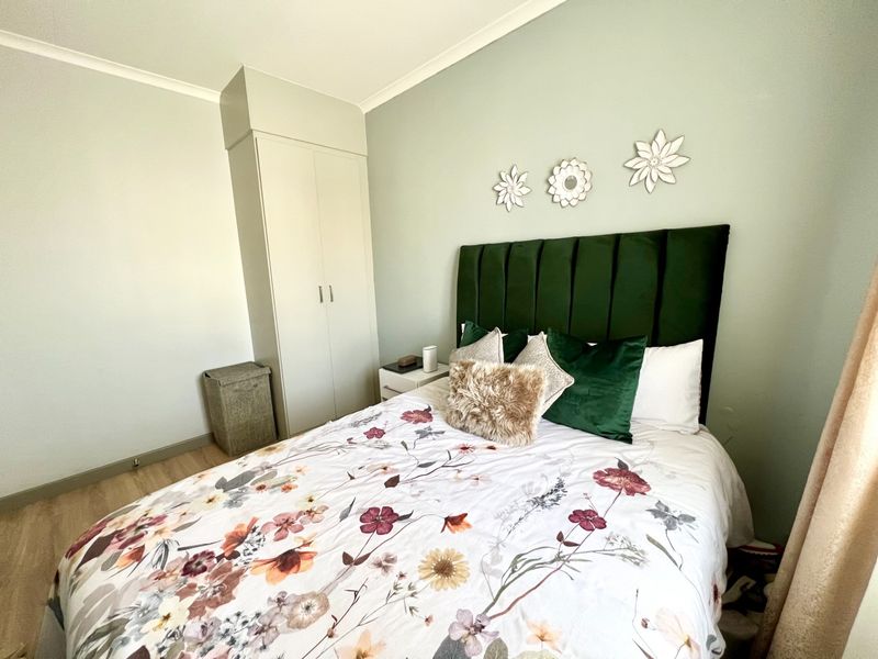 A well-maintained bedroom featuring light-toned laminate flooring, a built-in wardrobe, and neutral wall finishes.