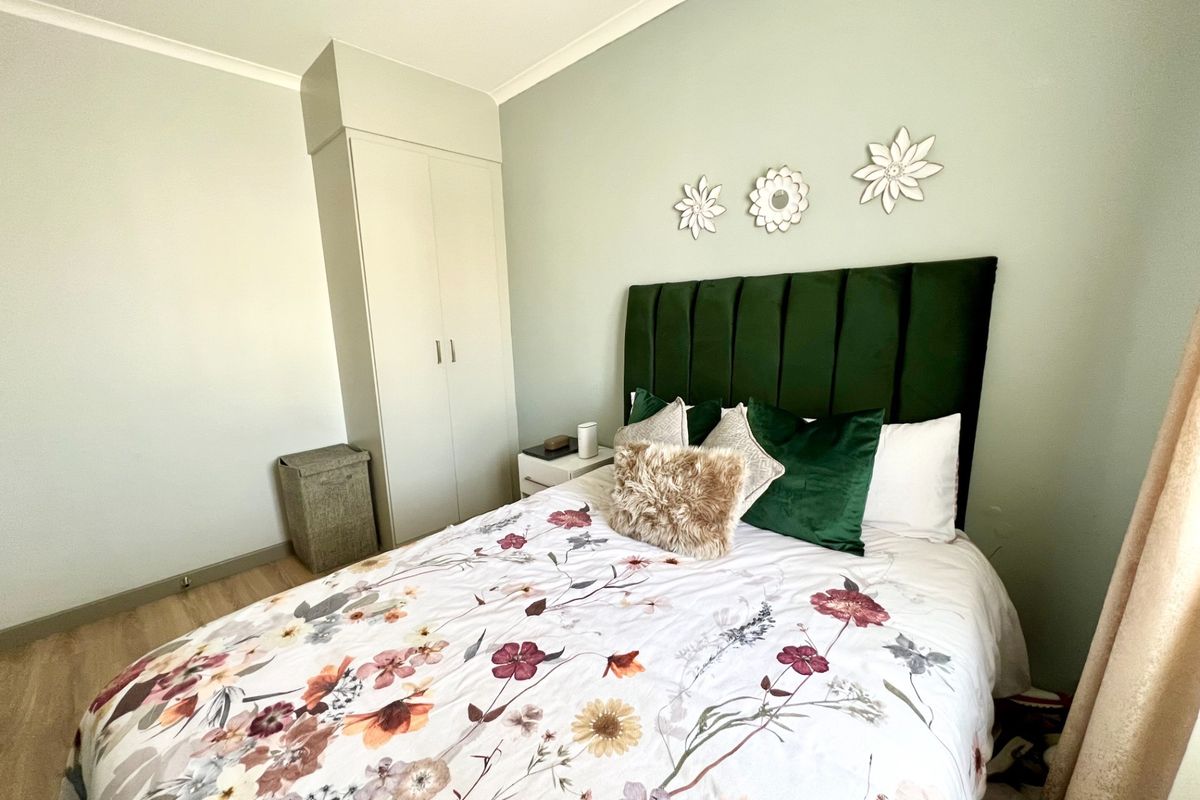 A well-maintained bedroom featuring light-toned laminate flooring, a built-in wardrobe, and neutral wall finishes.