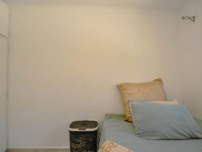 A simple bedroom featuring a built-in cupboard and neutral wall finishes, offering a functional space ready for personalization.