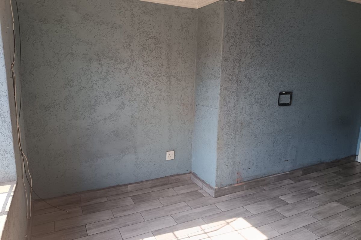 An empty living area featuring textured blue walls, crown molding, and modern wood-look floor tiles, providing a blank canvas for interior design.