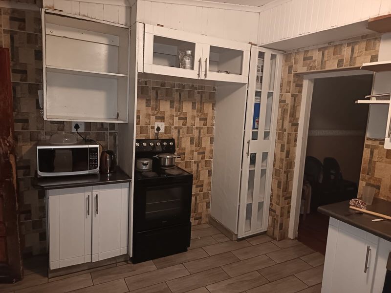 A dated kitchen featuring tiled walls, built-in cabinetry, and a freestanding oven, offering potential for a modern renovation.
