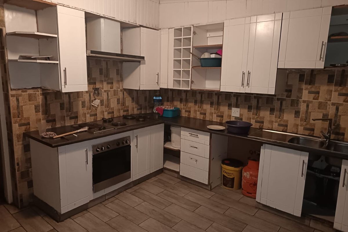 A functional kitchen featuring white cabinetry, built-in oven, gas hob, and tiled backsplash, currently requiring some maintenance and cosmetic updates.