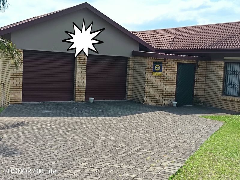 Front view of a residential property featuring a double garage, brick exterior, tiled roof, and a paved driveway.
