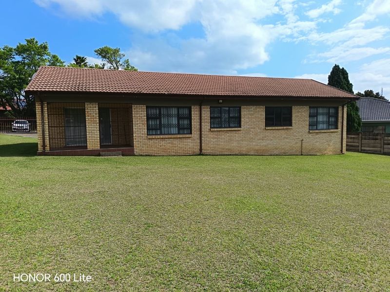 A single-story face brick house featuring a tiled roof, secure entrance with security gates, and burglar bars, set on a spacious lawn.
