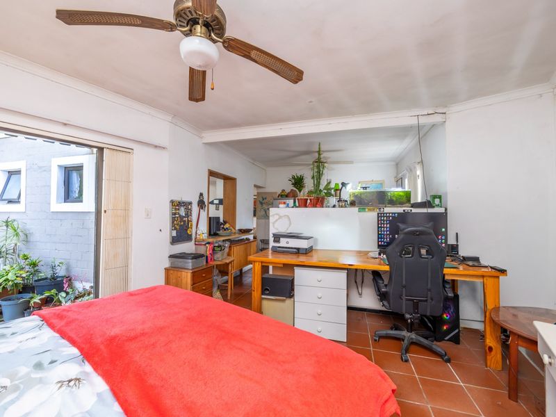 Bedroom featuring terracotta floor tiles, a ceiling fan, and a sliding glass door providing access to an outdoor area.