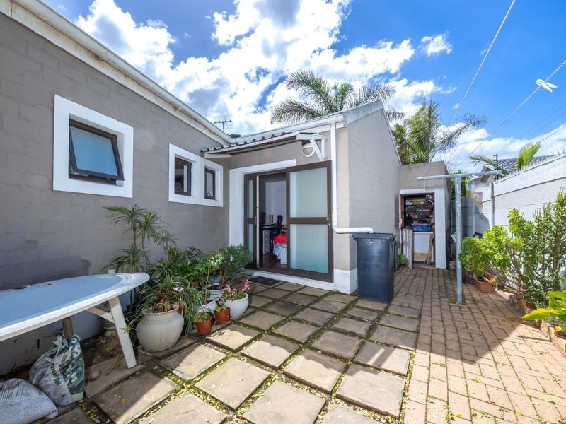 Rear exterior view featuring a paved patio area, sliding door access, and a small utility storage space.