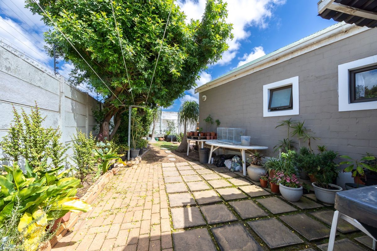 A rear garden area featuring a paved patio, precast boundary walling, and established greenery, offering a functional outdoor space for the property.